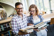 Two_happy_students_with_books_in_the_library_