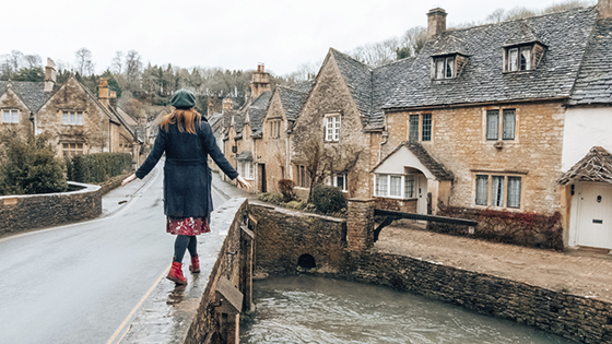 Woman balancing on bridge Castle Combe Wiltshire England 560x315