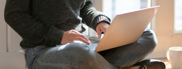 woman in gray sweater sitting on wooden floor typing on 37591151