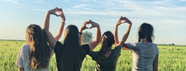 Teenagers linking hands in heart shape