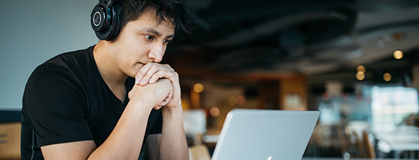 Man focussing on webinar laptop headphones 600x230