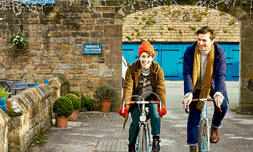Young-man-and-woman-with-bicycles-in-the-Peak-District-area-of-Derbyshire-370x223